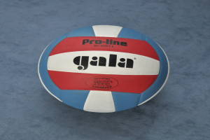 Ein blauer und roter Volleyball mit dem Wort "Gala" darauf, der auf einer blauen Fläche steht.