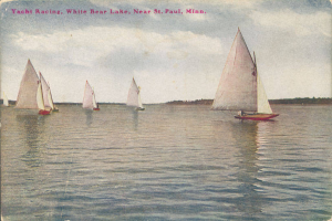 Eine Gruppe von Segelbooten auf einem Gewässer mit Bäumen im Hintergrund und einem klaren blauen Himmel, Text oben lautet "Yacht Racing, White Bear Lake, Near St. Paul, Minnesota".