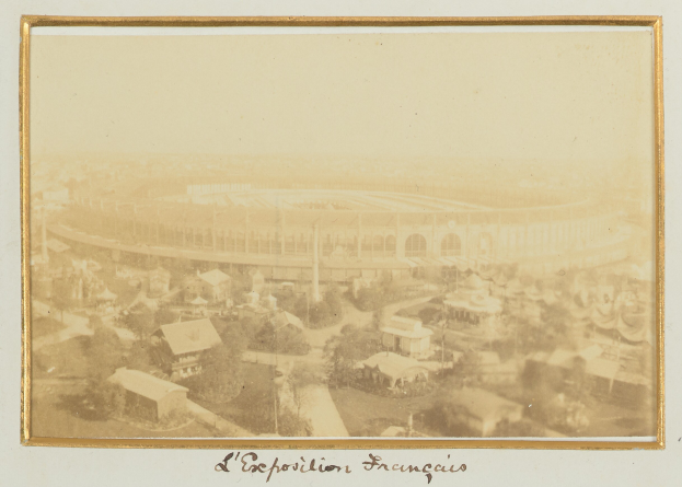 Altes Schwarz-Weiß-Foto eines Stadions in einer städtischen Umgebung, umgeben von Gebäuden, Bäumen und Strommasten, mit Text unten.