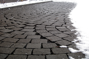 Eine Kopfsteinpflasterstraße mit leichtem Schnee, ein Zaun im Hintergrund, der eine friedliche Winterszene schafft.
