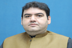 Ein Mann in einer braunen Weste und schwarzem Hemd steht vor einem blauen Hintergrund und sieht bedrückt und verzweifelt aus, wahrscheinlich wegen einer lebenslangen Haftstrafe.