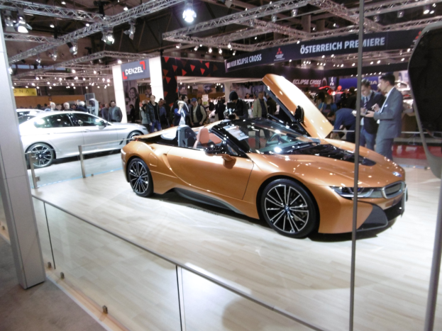 Schwarzer BMW i8 Roadster mit glänzender Lackierung und Chromakzenten auf der IAA in Frankfurt umgeben von formell gekleideten Besuchern.