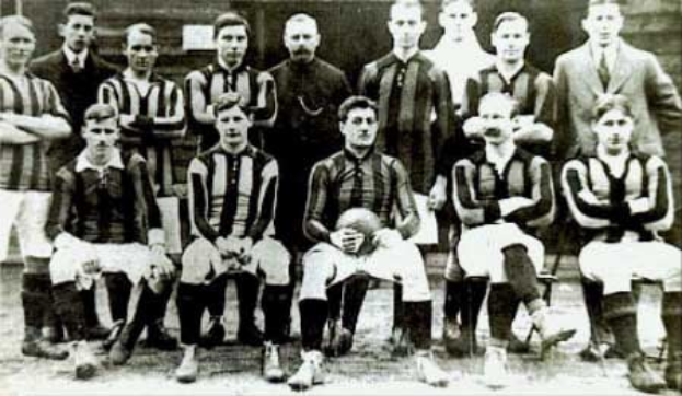 Ein Schwarz-Weiß-Foto einer Fußballmannschaft, die vor einer Wand steht oder sitzt, mit dem Text "Ballymena Football Club" unten.