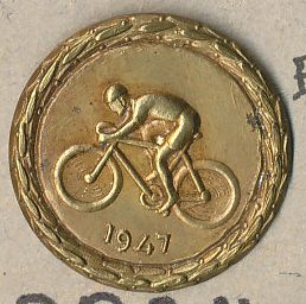 Eine Goldmedaille mit einem Mann auf einem Fahrrad, mit Text und Zahlen, die das Jahr angeben, in dem sie verliehen wurde.
