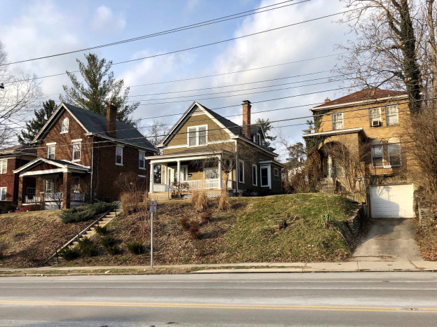 Reihe von Häusern mit Fenstern, Türen, Säulen, Geländern, Stufen, Pflanzen und einem Pfahl mit einer Tafel, die eines der teuersten Häuser in Detroit zum Verkauf anbietet.