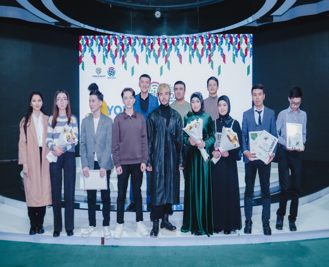 Gruppe von Menschen auf einer Bühne mit Blumensträußen und Urkunden, im Hintergrund ein "Youth Solar Awards 2019"-Plakat.