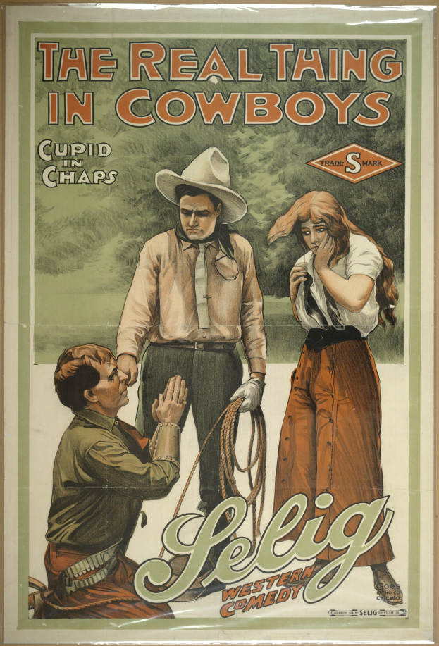 Plakat an einer Wand mit drei Personen - zwei Männer mit Cowboyhüten und eine Frau in einem langen Kleid - mit der Aufschrift "The Real Thing in Cowboys" darüber, vor einem hellgelben Hintergrund.