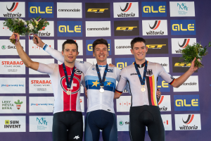 Drei Männer stehen auf einem Podest, jeder trägt eine Medaille und hält einen Blumenstrauß in der Hand, im Hintergrund ist ein "Giro d'Italia"-Schild zu sehen.