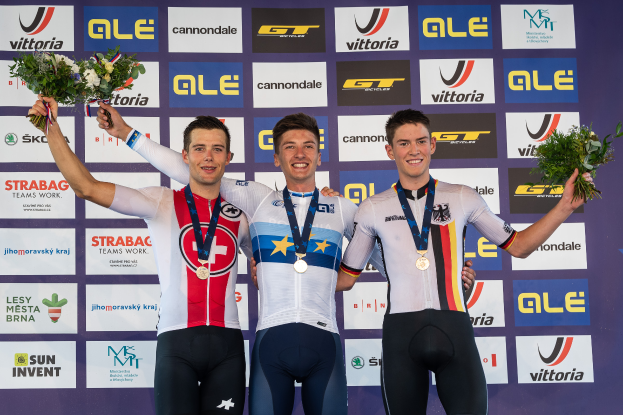 Drei Männer stehen auf einem Podest, jeder trägt eine Medaille und hält einen Blumenstrauß in der Hand, im Hintergrund ist ein "Giro d'Italia"-Schild zu sehen.