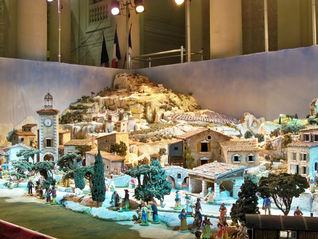 Ein detailliertes Miniatur-Modell einer Krippe in einem Museum ausgestellt, mit Figuren, Strukturen und beleuchteten Elementen unter Museumsbeleuchtung.