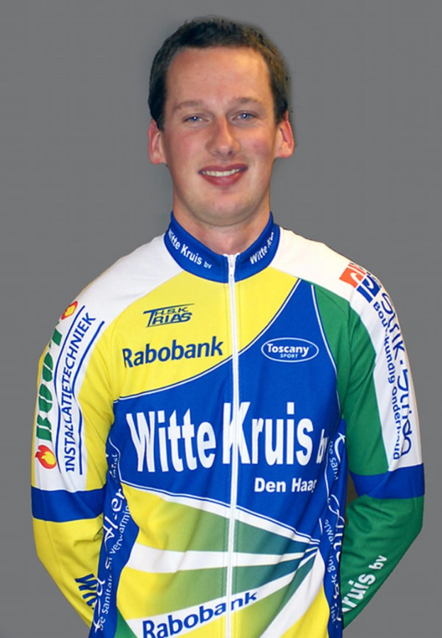 Ein männlicher Sportler posiert für ein Foto, trägt ein Shirt mit mehreren Sponsorennamen.