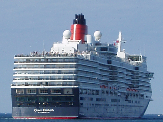 Großes Kreuzfahrtschiff Queen Elizabeth auf dem Meer mit anderen Booten und klarem blauen Himmel im Hintergrund.