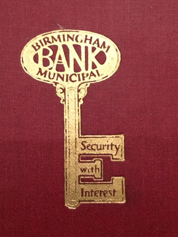 Ein rotes Buch mit einem goldenen Schlüssel darauf, beschriftet mit "Birmingham Bank Municipal Security with Interest".