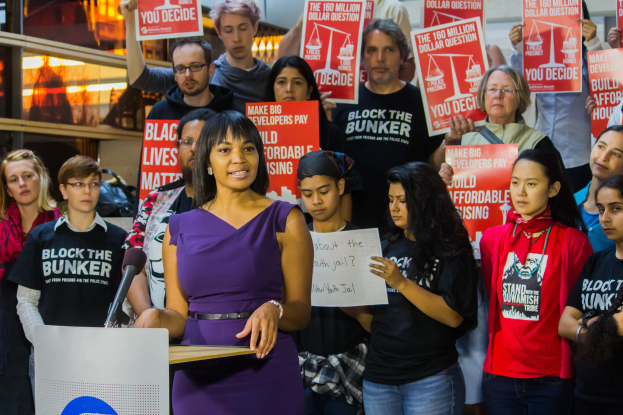 Eine Black-Lives-Matter-Aktivistin spricht vor einem Publikum mit Mikrofon, das eine Menge mit Schildern anspricht.