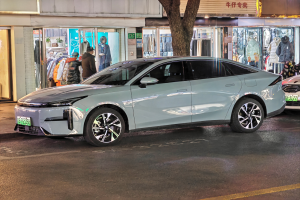 Ein Mitsubishi Lancer EV Elektroauto auf der Straße bei Nacht, umgeben von Gebäuden, Geschäften, Schaufensterpuppen, Schildern und Lichtern.