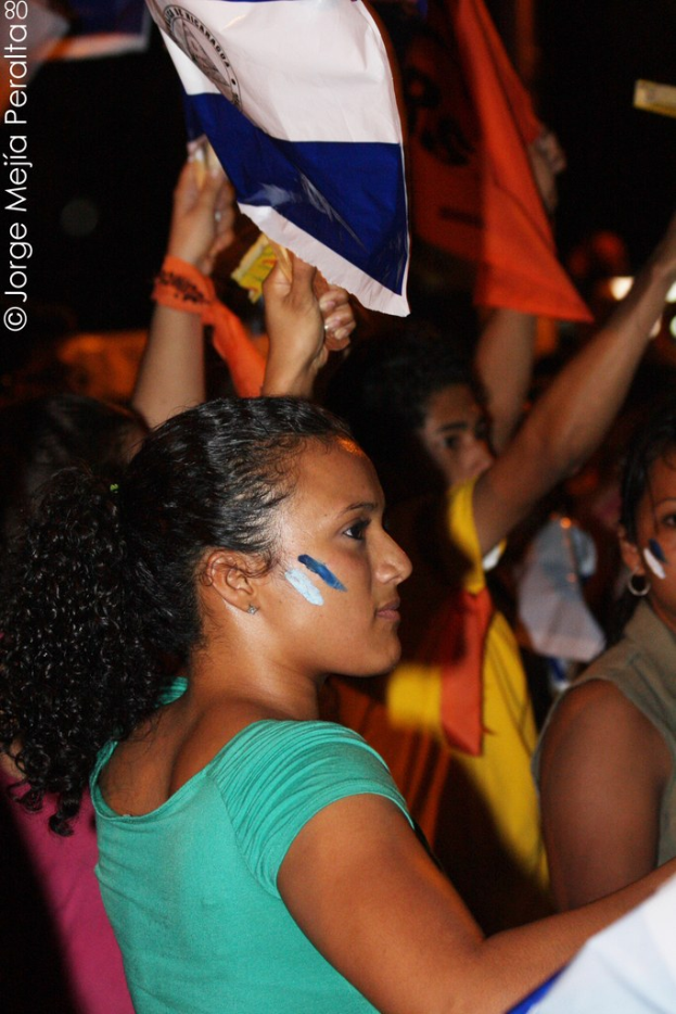 Frauen in grünen T-Shirts bei einer Demonstration, die weiße Decken in den Händen halten, mit vielen anderen Mädchen im Hintergrund.