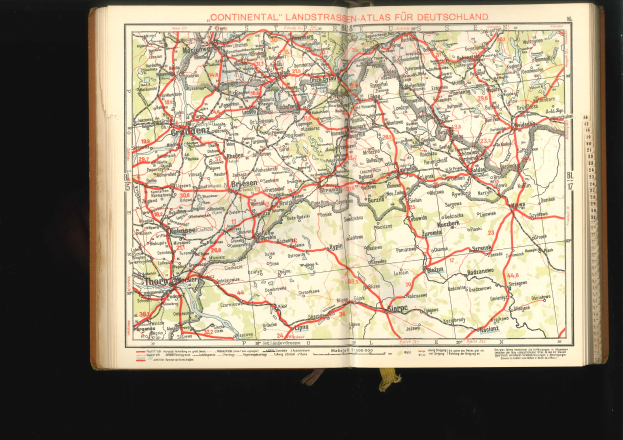 Offenes Buch mit einer detaillierten Karte von Deutschlands Straßen und Autobahnen vor einem schwarzen Hintergrund.
