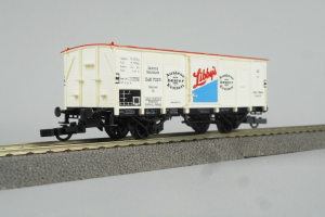 Ein rotes und weißes gestreiftes Spielzeugboxauto steht auf einer Schiene vor einem weißen Hintergrund.