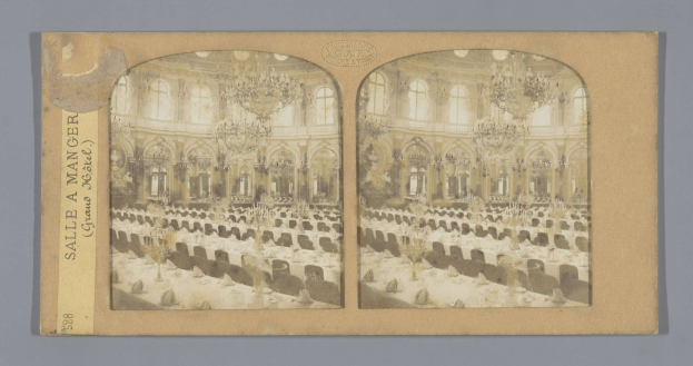 Ein altes Foto eines prächtigen Hotel-Speisesaals mit Tischen, Stühlen, Kronleuchtern und Fenstern, das den Text "Sale a Manger, Grand Hotel" auf der linken Seite zeigt.