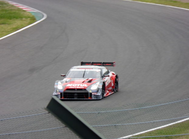 Nissan GT-R Nismo GT3 Rennwagen auf der Nürburgring 24 Stunden Strecke, umgeben von grünem Gras auf beiden Seiten.