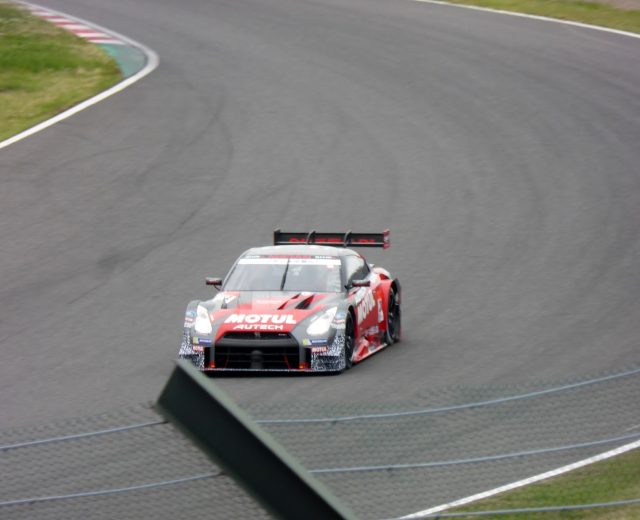 Nissan GT-R Nismo GT3 Rennwagen auf der Nürburgring 24 Stunden Strecke, umgeben von grünem Gras auf beiden Seiten.