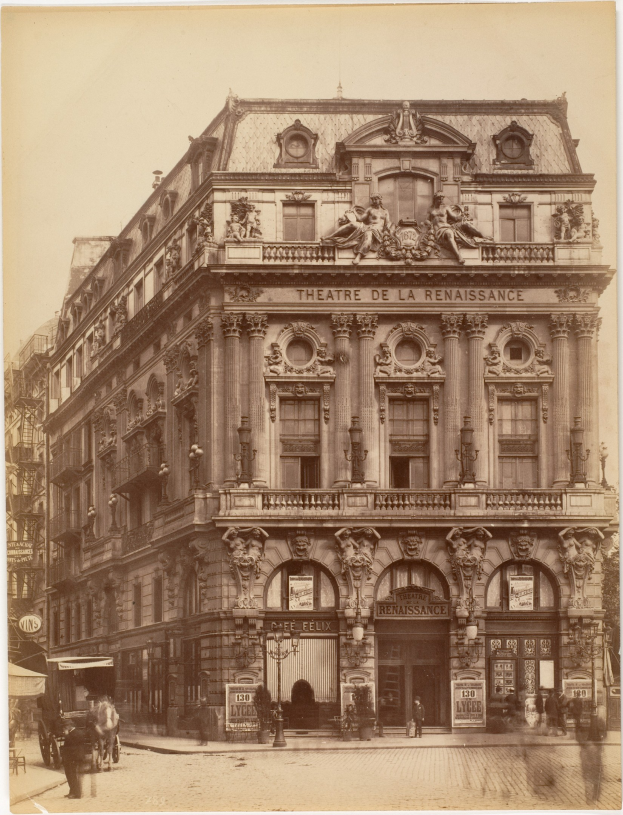 Schwarz-weiß-Fotografie des Théâtre de la Renaissance in Paris mit seiner prächtigen Fassade mit Fenstern, Säulen, Bögen und Skulpturen sowie einigen Menschen und Fahrzeugen auf der Straße davor und dem Himmel im Hintergrund.