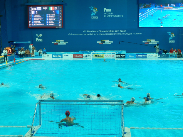 Wasserballspieler bei den FINA-Weltmeisterschaften 2016 in Kazan im Pool gegeneinander antretend, mit Zuschauern auf der linken Seite und einem Scoreboard im Hintergrund.