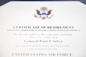 Rahmenurkunde zur Ruhestandsversetzung von der United States Air Force mit blauem Rand, die ein zentrales Sternschild-Logo innerhalb eines Lorbeerkranzes und eine "Ruhestandsversetzung" -Bannerschrift in schwarzer Tinte zeigt.